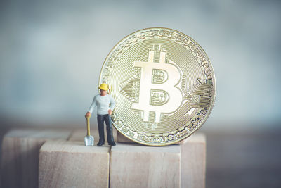 Close-up of male worker figurine with bitcoin on wood