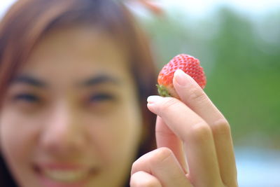 Close-up portrait of woman holding strawberry