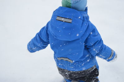 Rear view of boy walking on snow