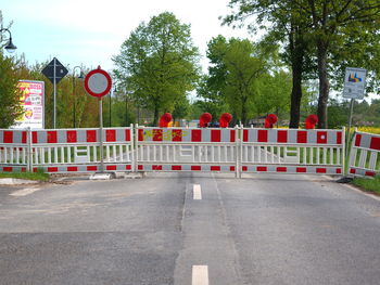 Road sign by cars on street against trees in city