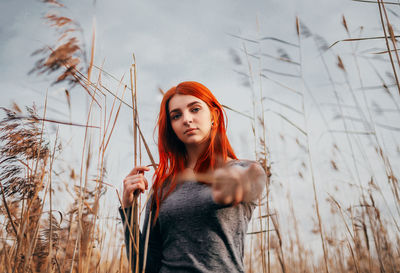 Portrait of beautiful young woman standing against plants