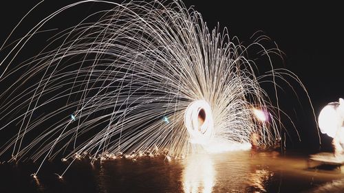 Firework display over river against sky at night