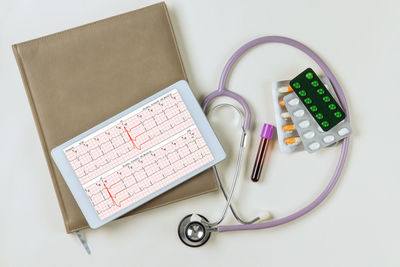 High angle view of stethoscope with clipboard on white background