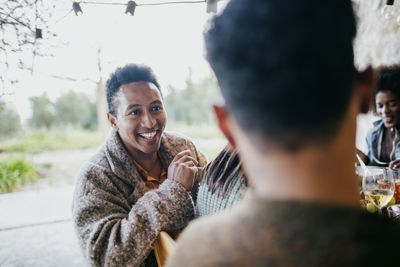 Smiling man listening to friend during party at backyard patio