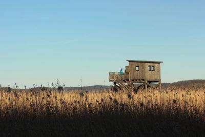 Lifeguard hut amidst field against clear sky