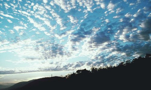 Silhouette of trees against cloudy sky
