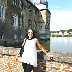 Portrait of smiling young woman standing against building in city