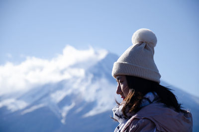 Young woman wearing warm clothing against blue sky