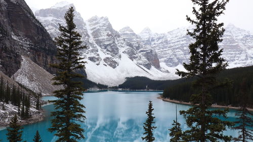 Scenic view of lake by snowcapped mountains against sky