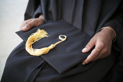 Mid-section of woman holding mortarboard