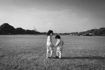 Friends standing on field against sky