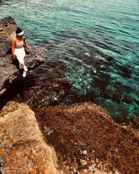 High angle view of woman sitting on rock at beach