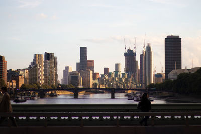 Modern london skyline by river thames against sky.