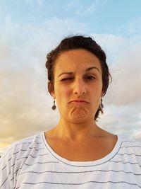 Portrait of woman winking against sky