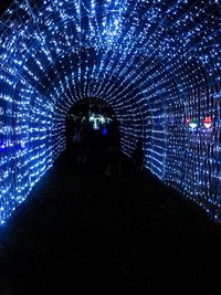 Rear view of silhouette people standing in illuminated tunnel