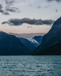 Layered mountain range over a fjord water and dusk sky