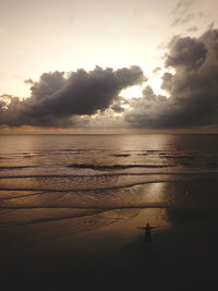 Silhouette woman walking at beach against sky during sunset