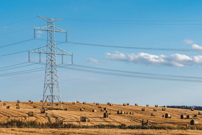 Straw bales on the field near high electricity pylons