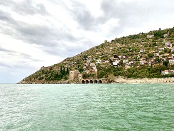 Scenic view of sea by buildings against sky