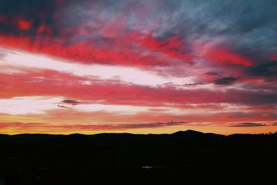 Silhouette landscape against dramatic sky during sunset