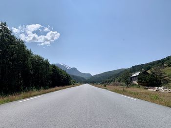 Empty road amidst trees against sky