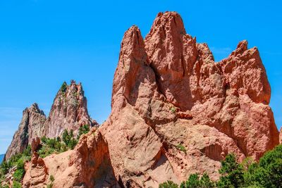 Low angle view of rocky mountain against blue sky