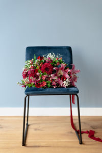 Bunch of flowers in burgundy tones on a dark blue velvet chair.