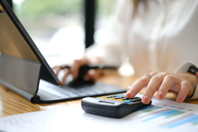 Midsection of woman using calculator at table