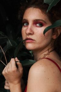 Close-up portrait of young woman holding sunglasses