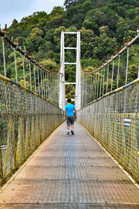 Rear view of boy walking on footbridge