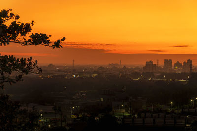 High angle view of silhouette trees and buildings against sky at sunset