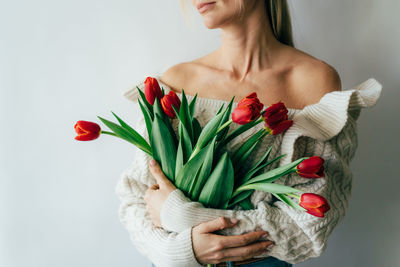 Midsection of woman holding red rose against white background