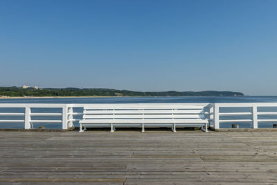 Pier over sea against clear blue sky