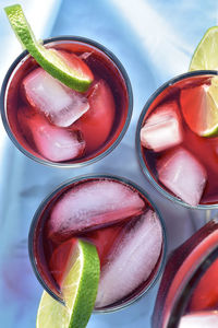 Above view of drink glasses of red hibiscus flower iced tea with ice cubes with lime slices garnish