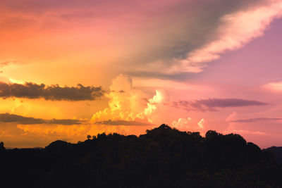 Silhouette landscape against dramatic sky during sunset