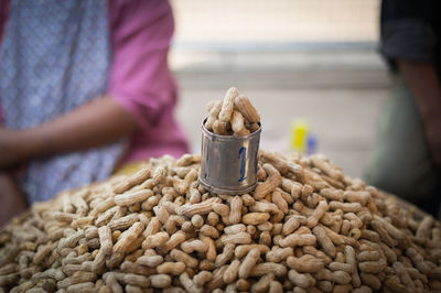 Metallic container on top of peanut heap at market stall