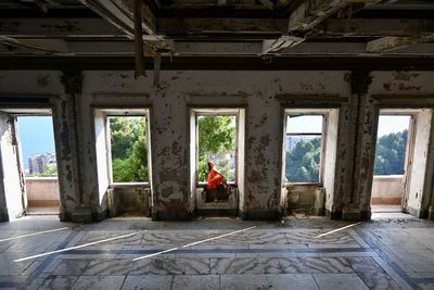 Rear view of woman sitting in abandoned building