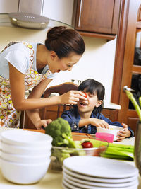 Happy mother playing with daughter in kitchen