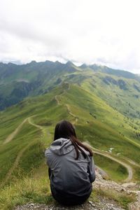 Rear view of teenage girl sitting on mountain