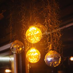 Low angle view of illuminated light bulbs hanging from ceiling