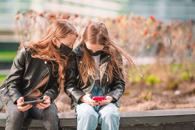 Full length of woman using mobile phone outdoors