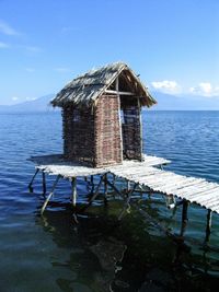 Lifeguard hut by sea against blue sky