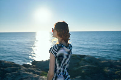 Woman standing by sea against sky