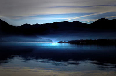 Scenic view of sea and silhouette mountains against sky