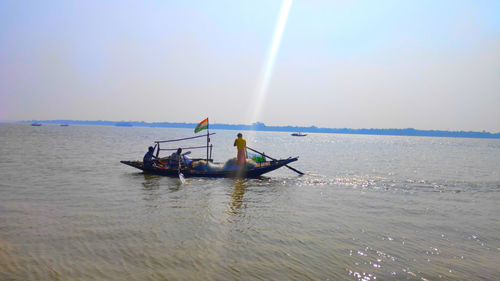 People in boat on sea against sky