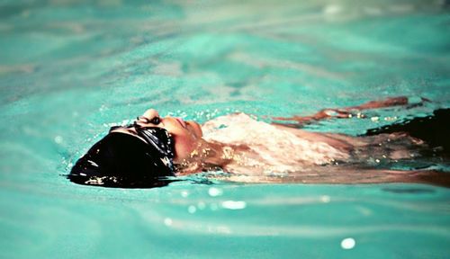 High angle view of shirtless boy swimming in pool