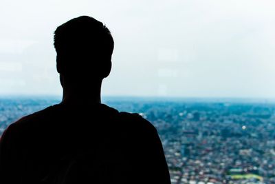Rear view of silhouette man looking at cityscape