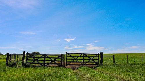 Wooden gate on field against sky