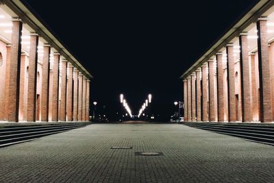 Pathway amidst illuminated corridors at night