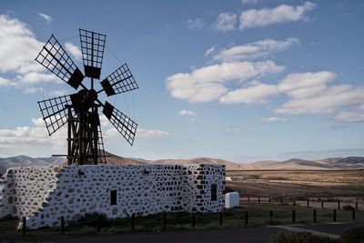 Traditional old windmill on field against sky